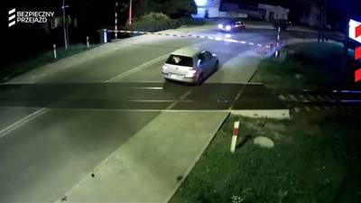 Automobilist kruipt door oog van de naald bij spoorwegovergang