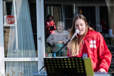 Bewoners Theresiahof Bornerbroek zingen vanachter het glas luidkeels met het bandje mee