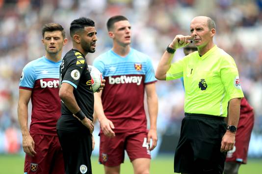 Scheidsrechter Mike Dean luistert naar de instructies van de VAR.
