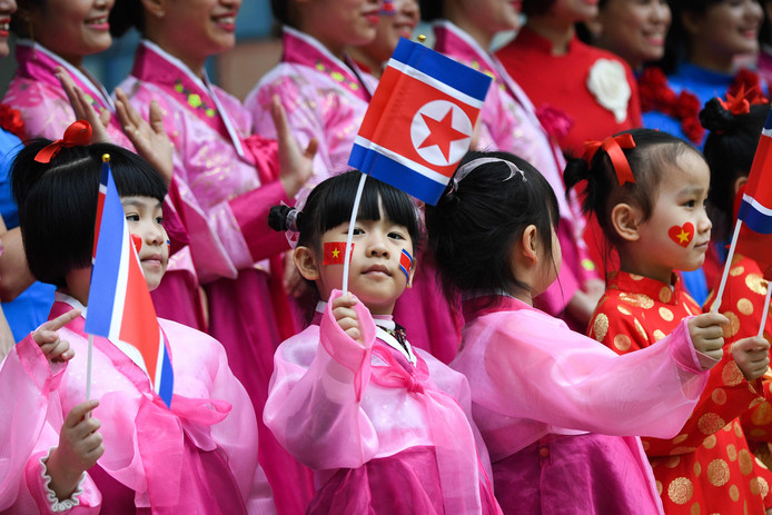 Vietnameese kinderen wuiven met Noord-Koreaanse vlaggetjes.