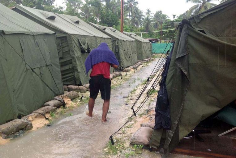 Een man loopt door de regen op het ‘regional processing centre’ op Manus Island, Papoea-Nieuw-Guinea. De foto is niet gedateerd, maar ontvangen op 18 februari 2014. Het beeld is afkomstig van Behrouz Boochani, die sinds 2013 op het detentiecentrum asiel van de Australische overheid hoopt te krijgen.  Beeld AFP