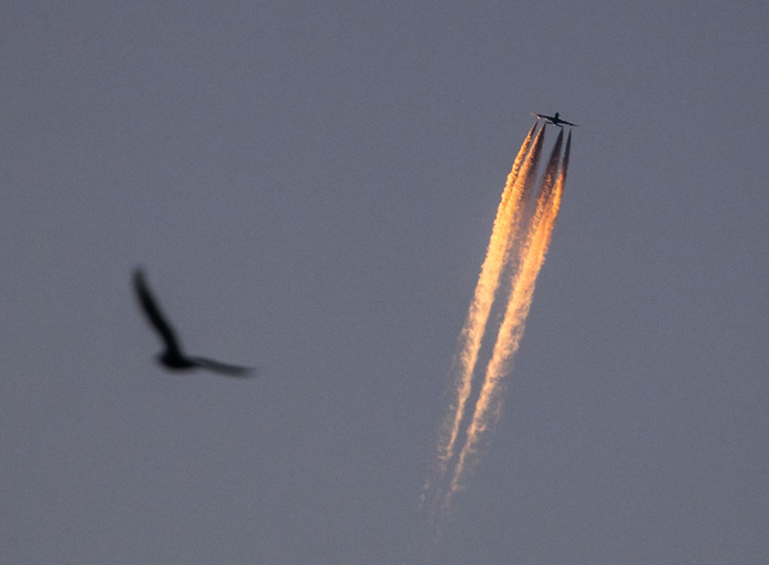 Een vliegtuig trekt sporen door de lucht in de ochtendzon boven Frankfurt am Main, Duitsland. Foto Frank Rumpenhorst