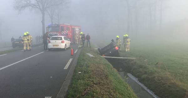 Auto op de kop in sloot na frontale aanrijding in mist .