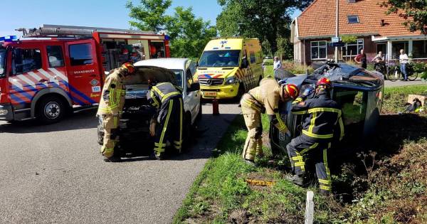 Frontale botsing in Mander: Auto op zijn kant en twee gewonden.