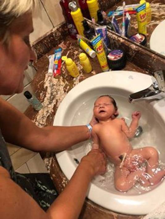 Oma Sylvia baddert Yassin in in de wasbak van hun hotelkamer