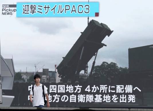 Een Japanse jongen loopt langs een televisiescherm waarop beelden van een Amerikaanse PAC-3 Patriot-installatie die Japan moet beschermen tegen raketten uit Noord-Korea.