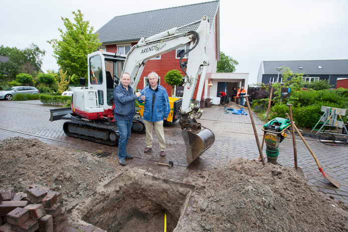 Robert van den Breemen heft in 2014 het glas met zijn vader Bart op de aansluiting op het gasnet. Hij is de eerste bewoner in ‘ecowijk’ De Teuge die beschikt over gasgestookte cv-ketel. Achter hem werken medewerkers van Van Dalen Installatietechniek de warmtepomp het huis uit.