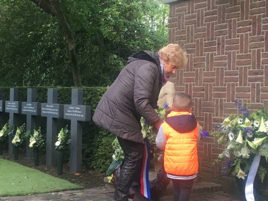 De echtgenote van een zoon van één van de verzetshelden en jonge bezoeker leggen een krans tijdens Dodenherdenking op begraafplaats Westduin in Den Haag.