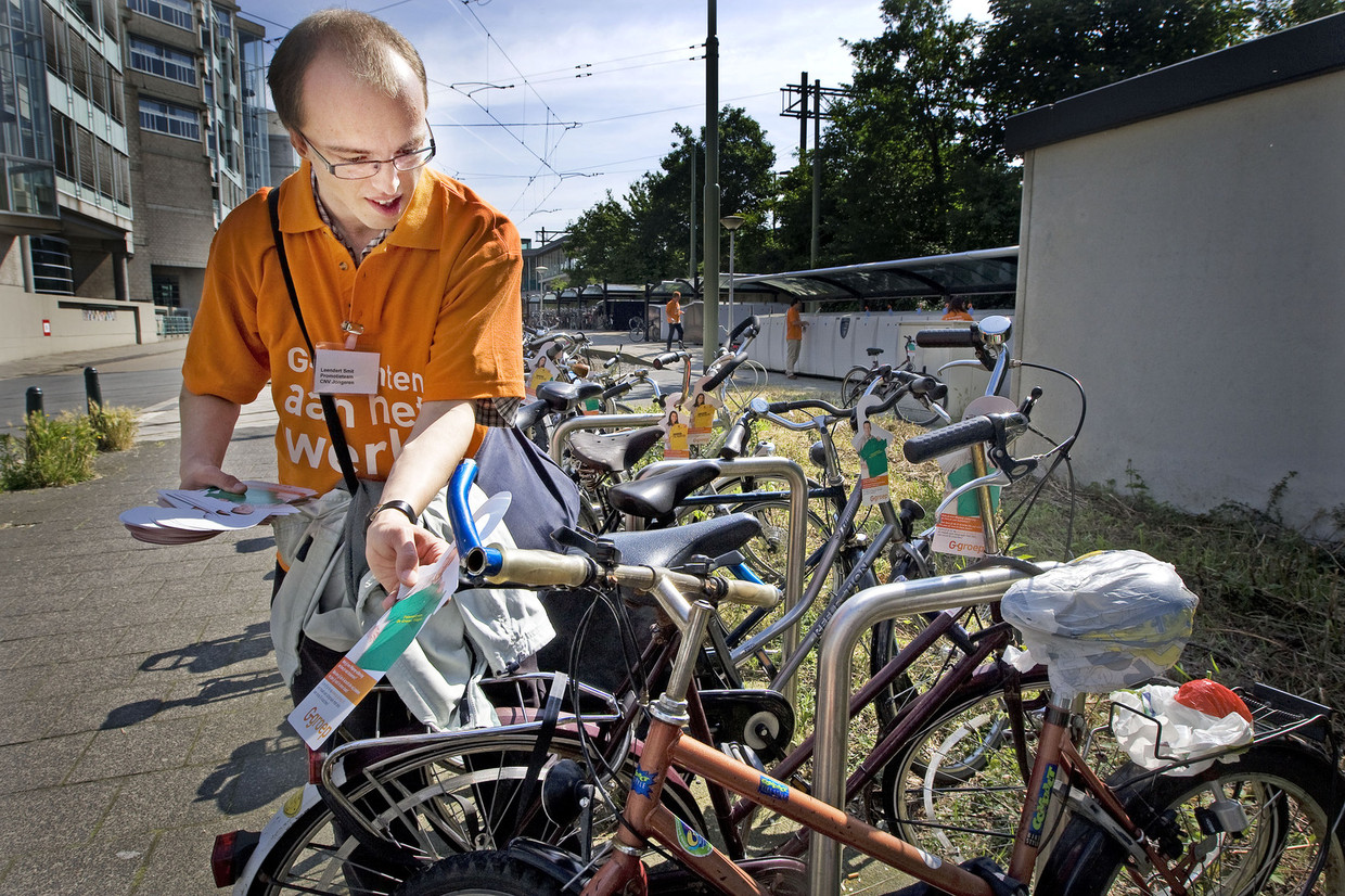 Een wajonger hangt flyers op aan fietsen om actie te voeren voor banen voor jonggehandicapten.