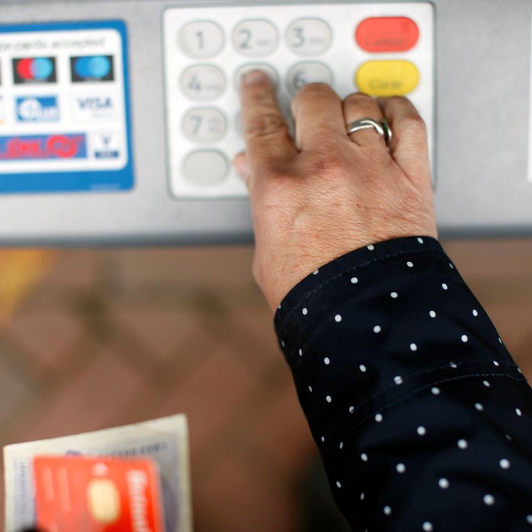 Een oudere vrouw haalt met behulp van een pinpas geld uit een geldautomaat.
 Beeld Hollandse Hoogte / Richard Brocken