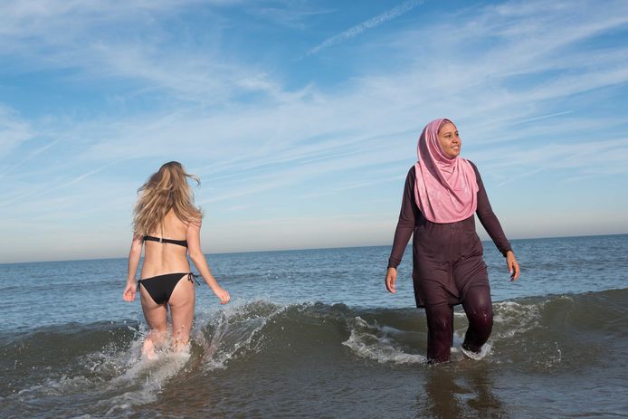 Een vrouw in boerkini en een meisje in bikini in zee.